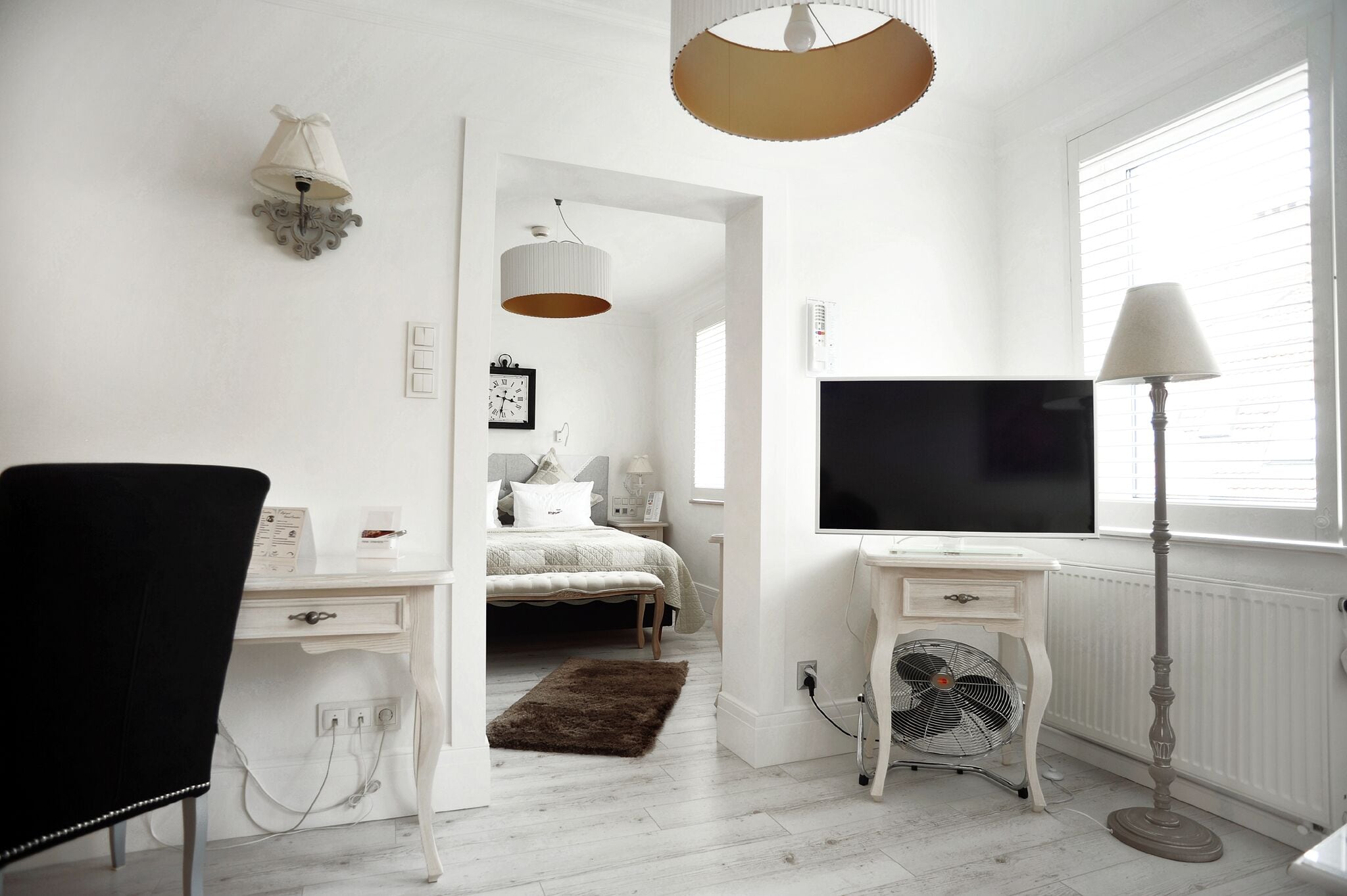 A bedroom with a bed, bedside table, lamp, and a TV.