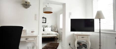 A bedroom with a bed, bedside table, lamp, and a TV.