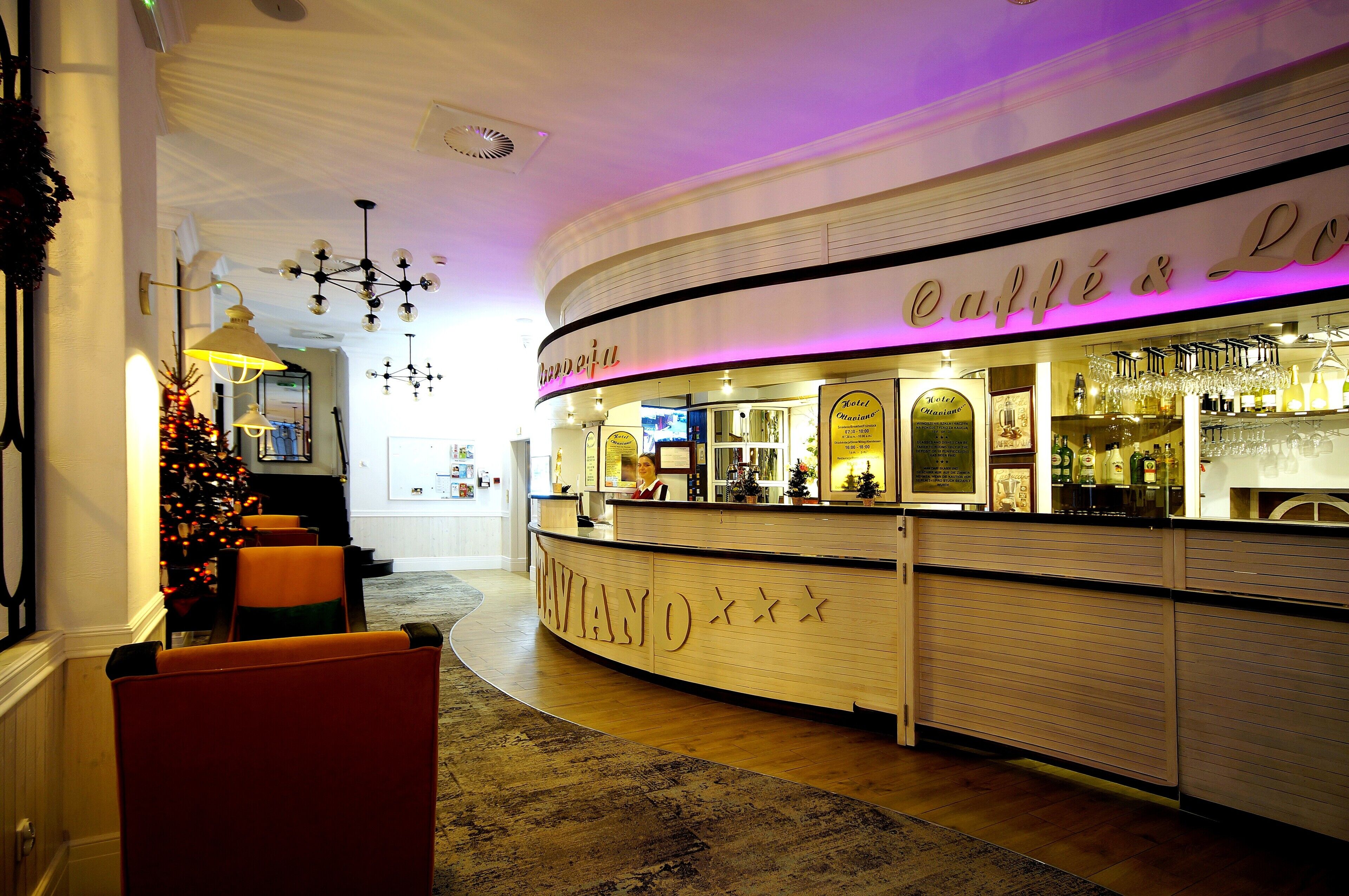 A hotel lobby with a reception desk, a Christmas tree, and a bar area.