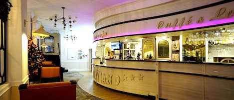 Un hall d’hôtel comprenant un comptoir d’accueil, un sapin de Noël et un espace bar.