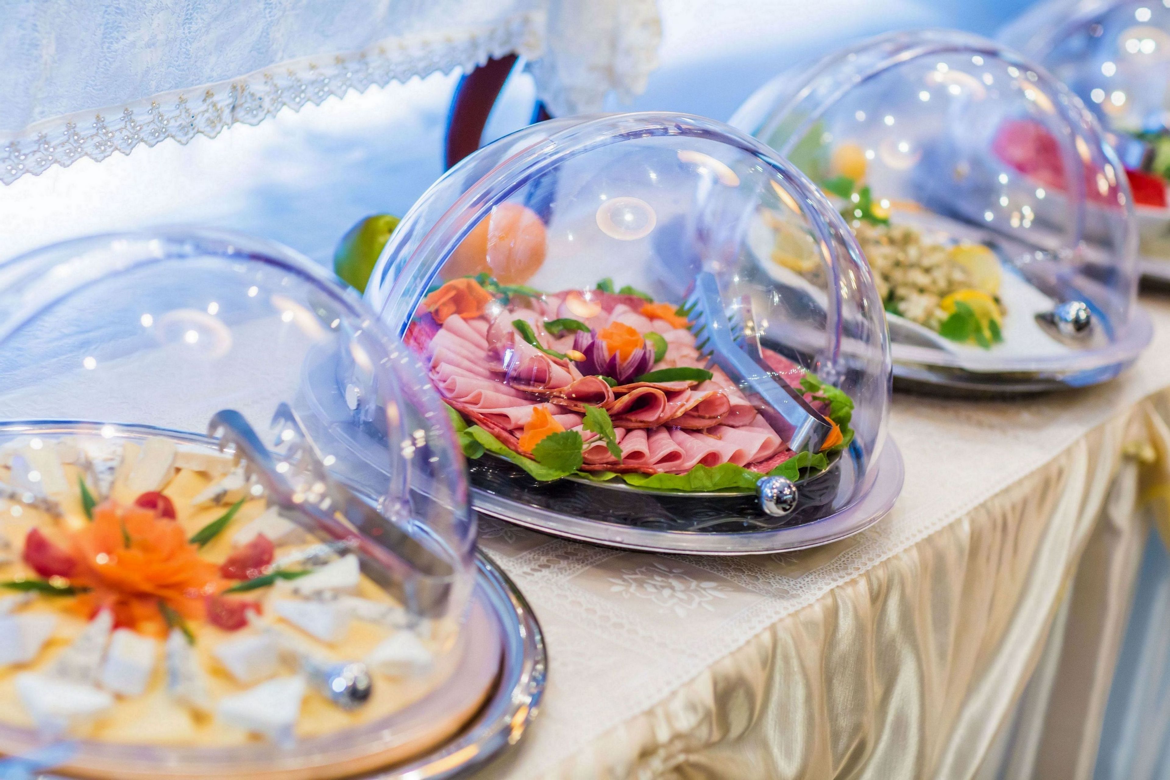 Une table de buffet proposant divers plats, présentés sous des cloches transparentes.