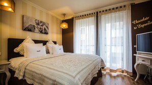 Una cama bien hecha con sábanas y almohadas blancas, un cuadro en la pared y un letrero que dice 'Chocolate to Espresso'.