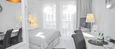 A hotel room with a bed, a desk with a chair, a television, a clock, and a window with curtains.