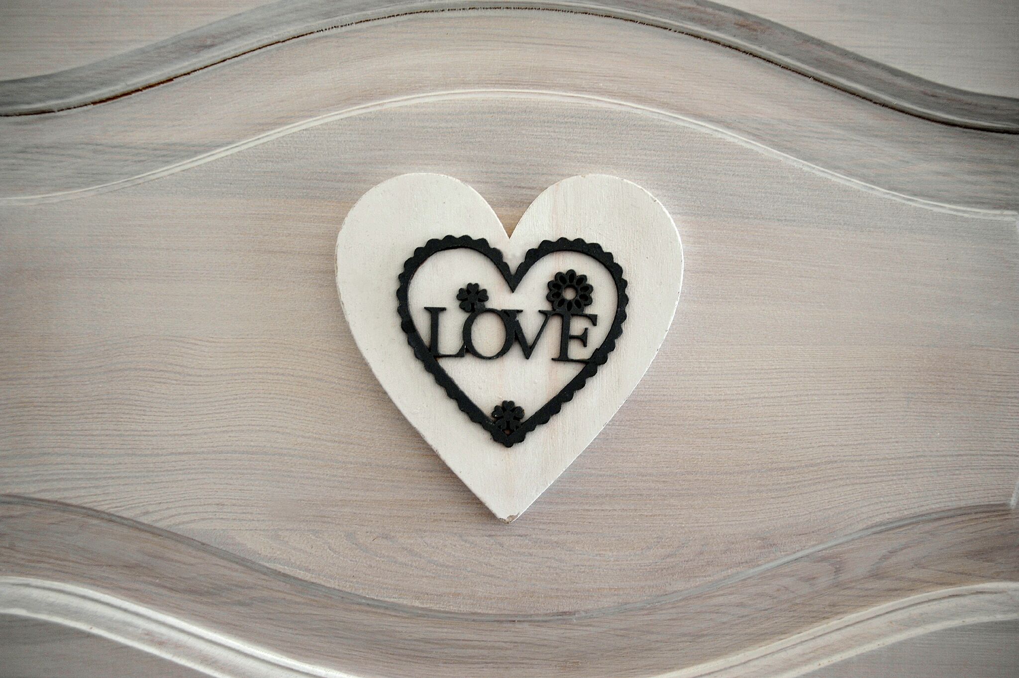 A heart-shaped decoration with the word "LOVE" on a wooden surface.