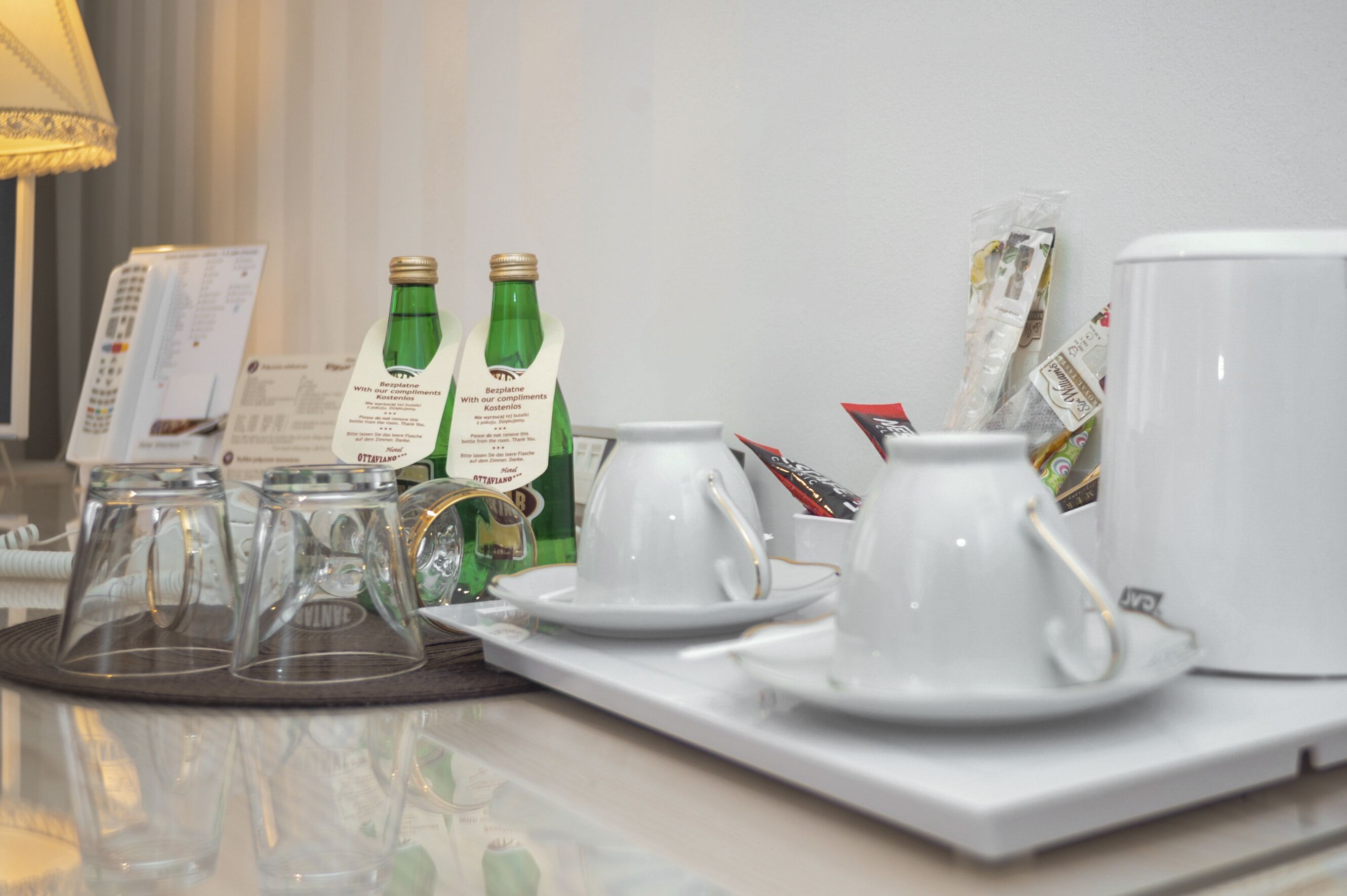 Un plateau de petit-déjeuner installé dans une chambre d’hôtel, comprenant une théière, des tasses et des bouteilles.
