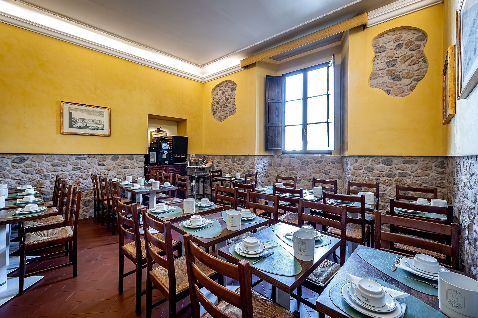 A restaurant with yellow walls, stone accents, and multiple tables set for dining.