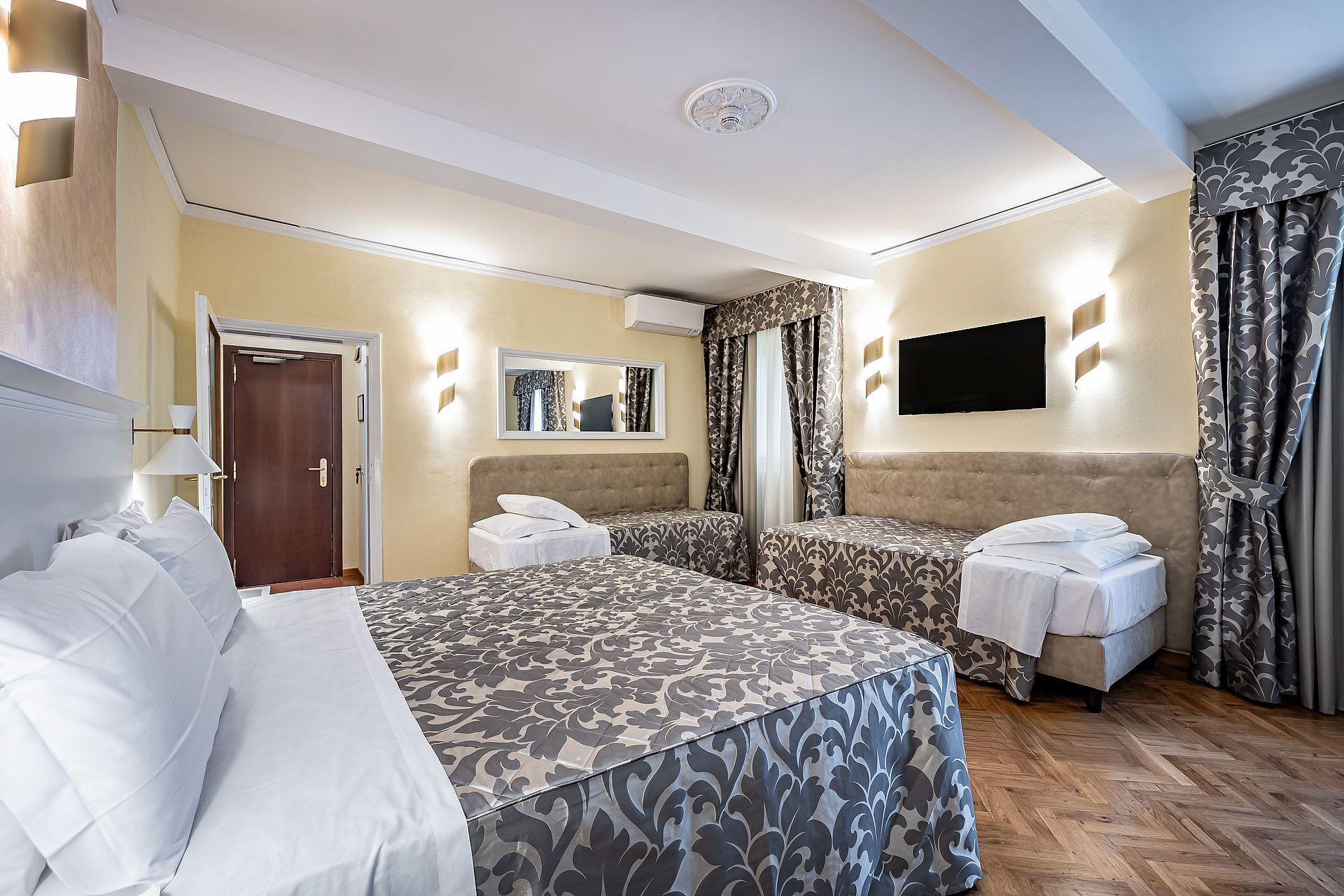 Habitación de hotel con dos camas, televisión y espejo.