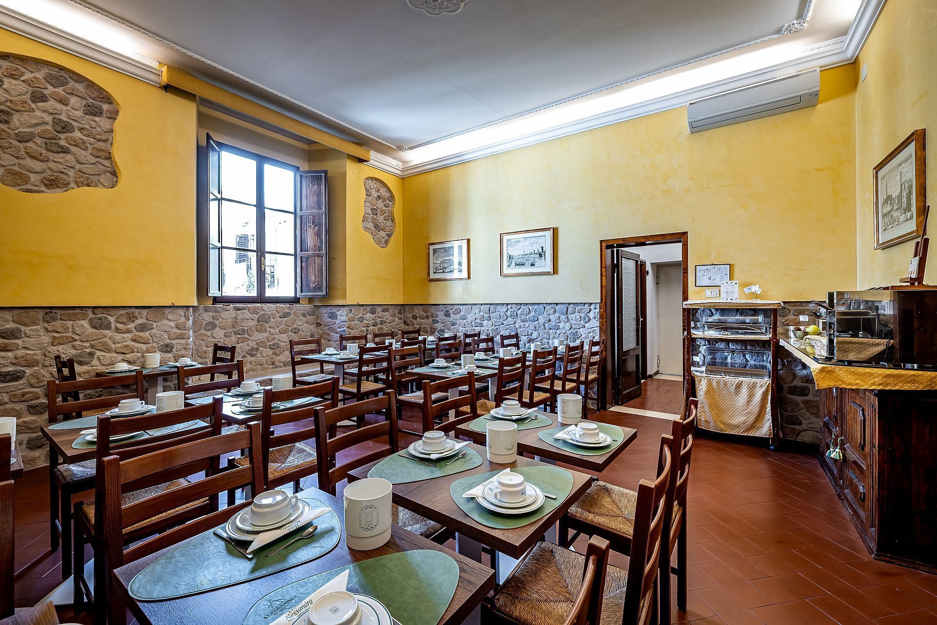 A restaurant with multiple tables, chairs, and a stone wall.