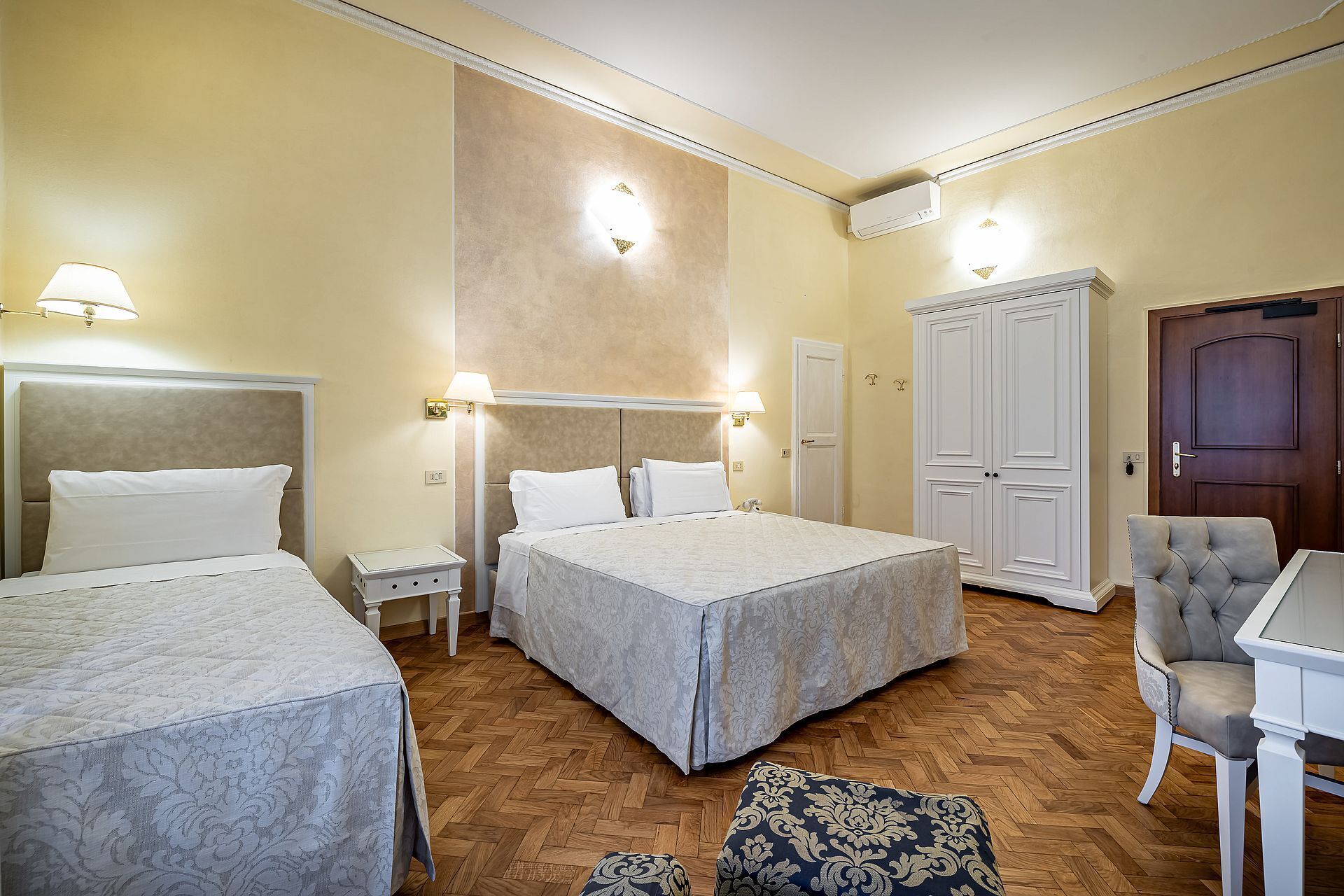 A hotel room with two beds, a wardrobe, a desk, and a chair.