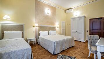 A hotel room with two beds, a wardrobe, a desk, and a chair.