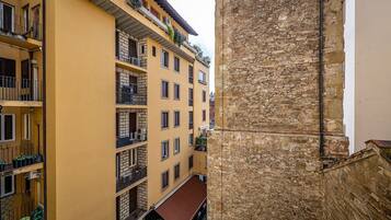 Un edificio de varios pisos con balcones, un muro de piedra y un toldo rojo.