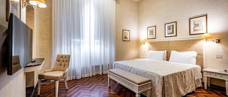A hotel room with a large bed, a chair, a bench, a TV, and a desk.