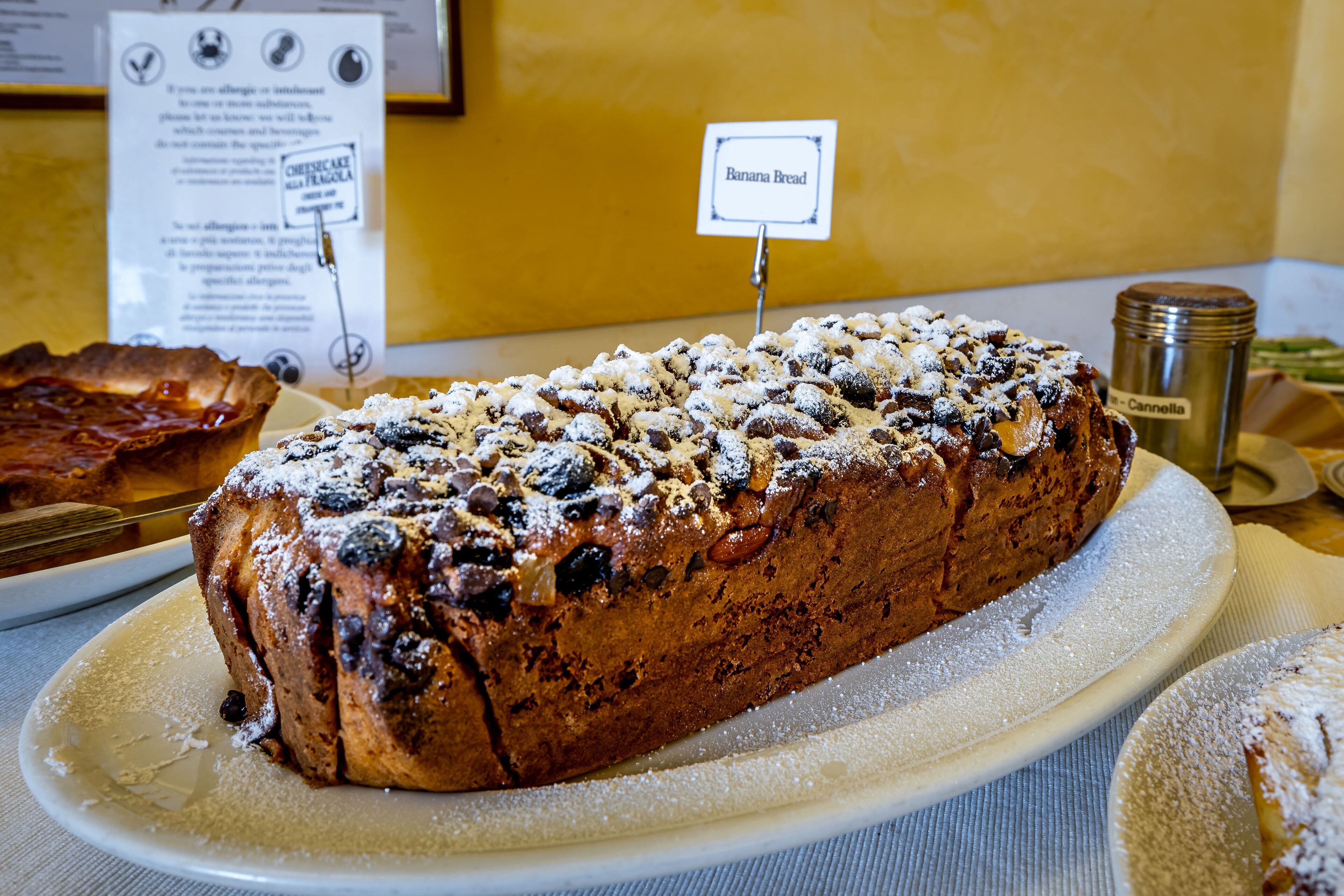 A loaf of banana bread on a plate with a sign above it.