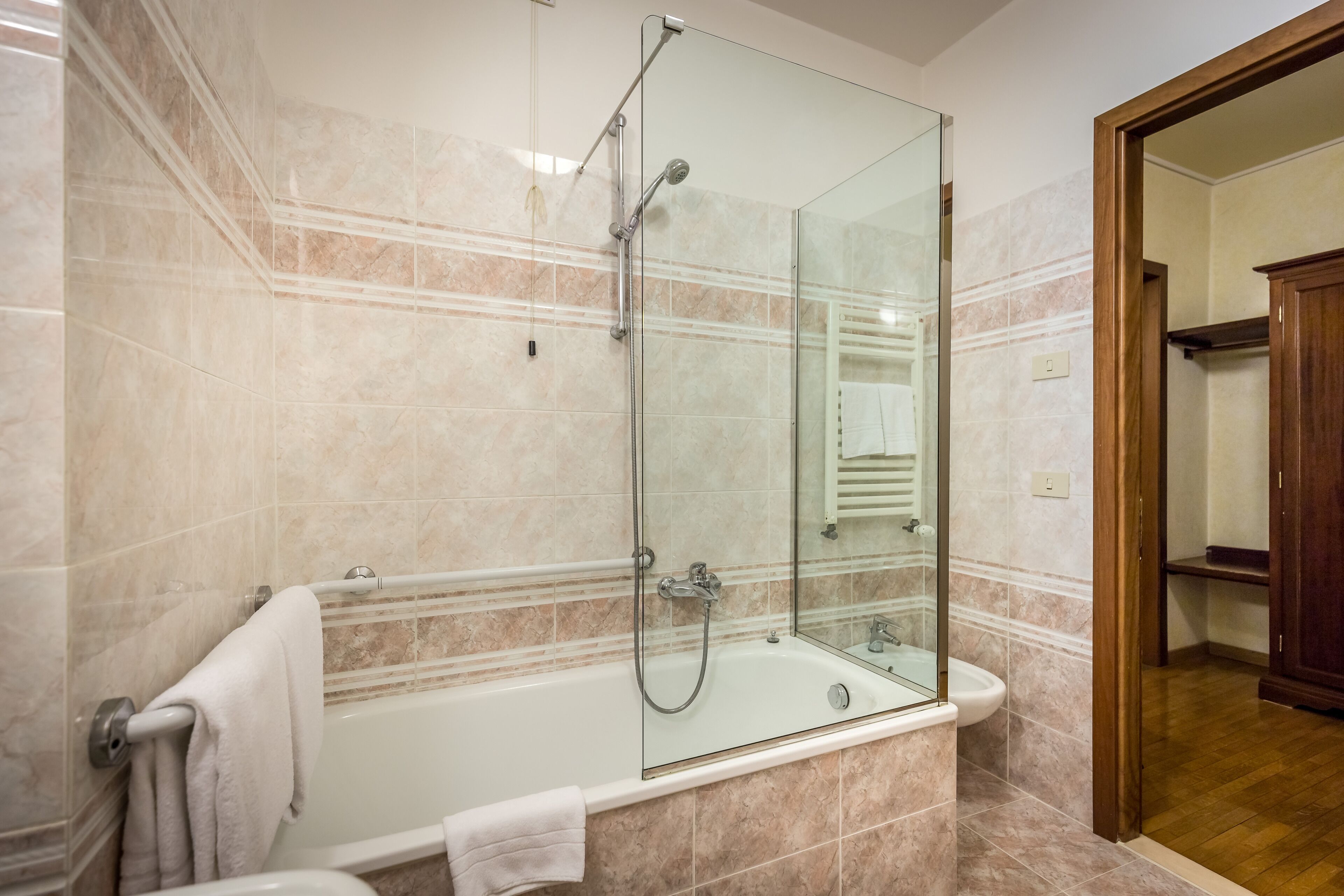 Ein modernes Badezimmer mit einer gläsernen Duschkabine, einer Badewanne und Marmorfliesen.