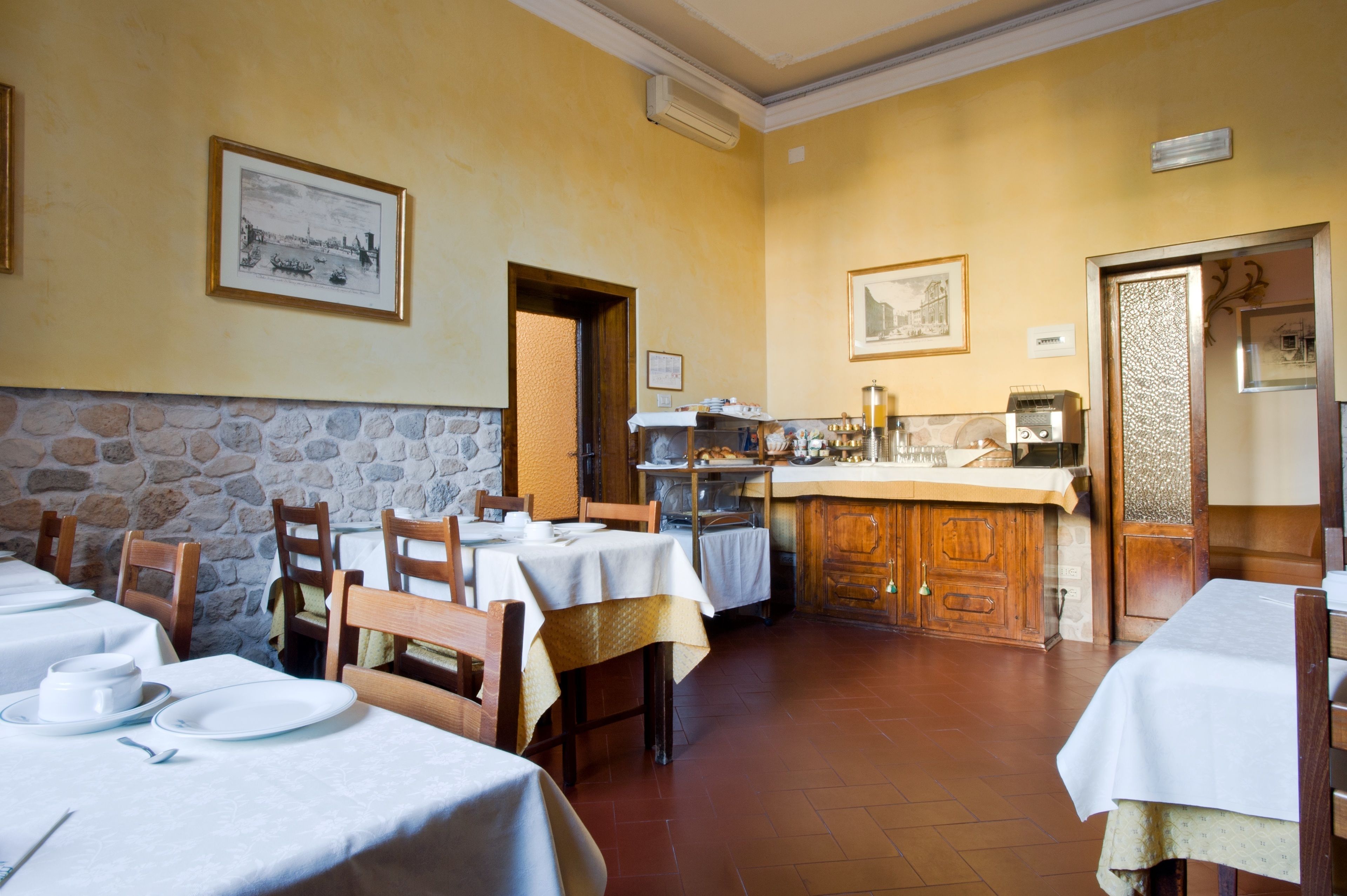 A restaurant with multiple tables, a stone wall, and a kitchen area.