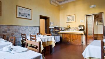 A restaurant with multiple tables, a stone wall, and a kitchen area.