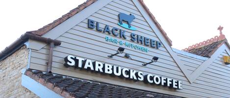 Un edificio con un letrero que indica 'Black Sheep Bar & Kitchen' y 'Starbucks Coffee'.