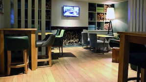 A cozy living room with a fireplace, wooden furniture, and a television mounted on the wall. - Lodge at Bristol (Bristol)