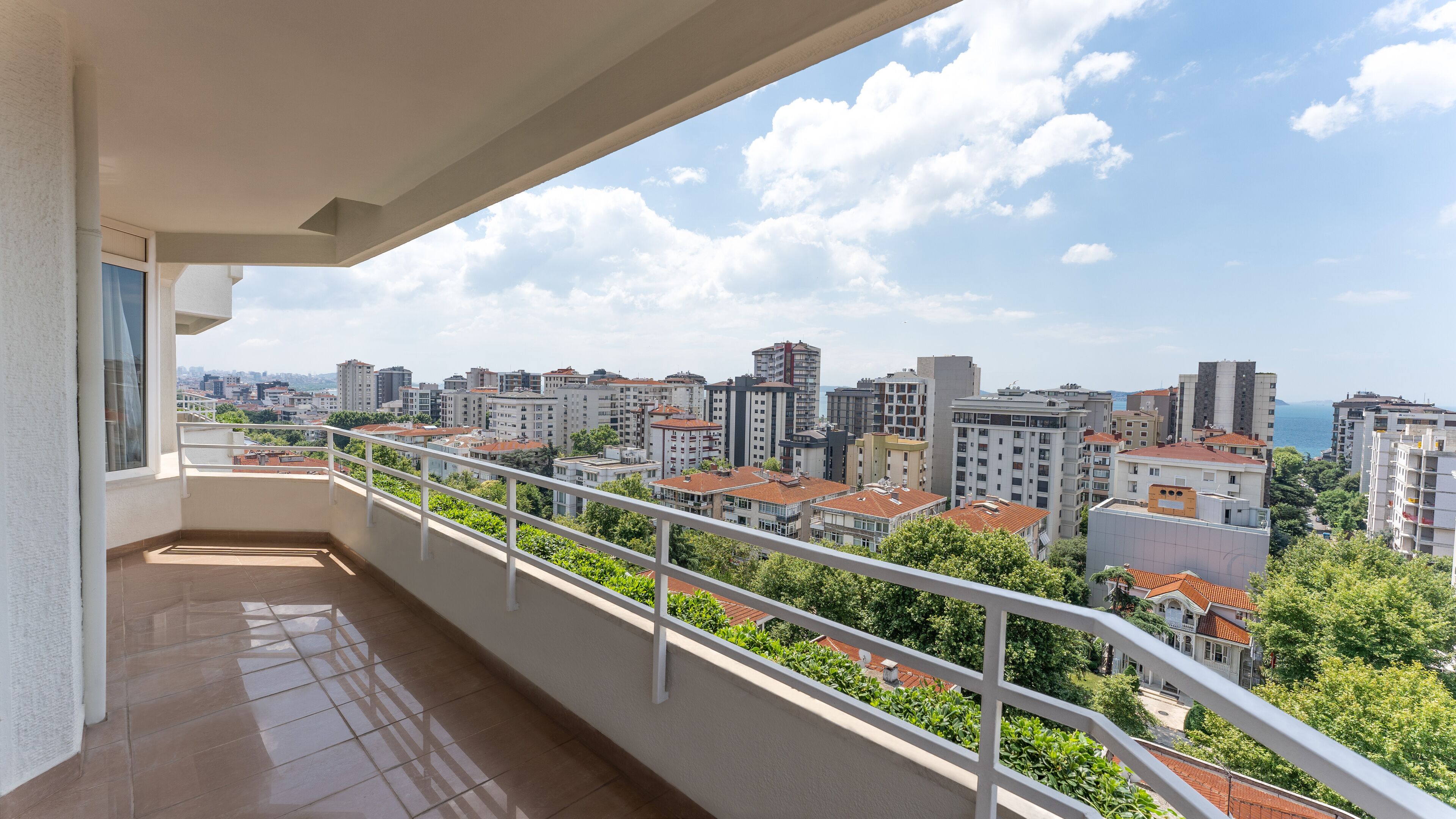 A balcony with a view of a cityscape and the sea.