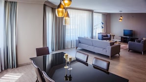 A modern living room with a sofa, a dining table with chairs, a TV, and a chandelier. - The Marmara Suadiye Residence (Istanbul)