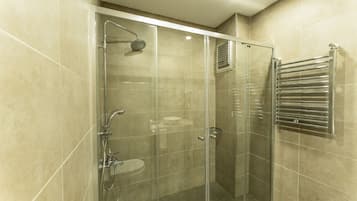 A glass-enclosed shower with a handheld showerhead and a handheld faucet.