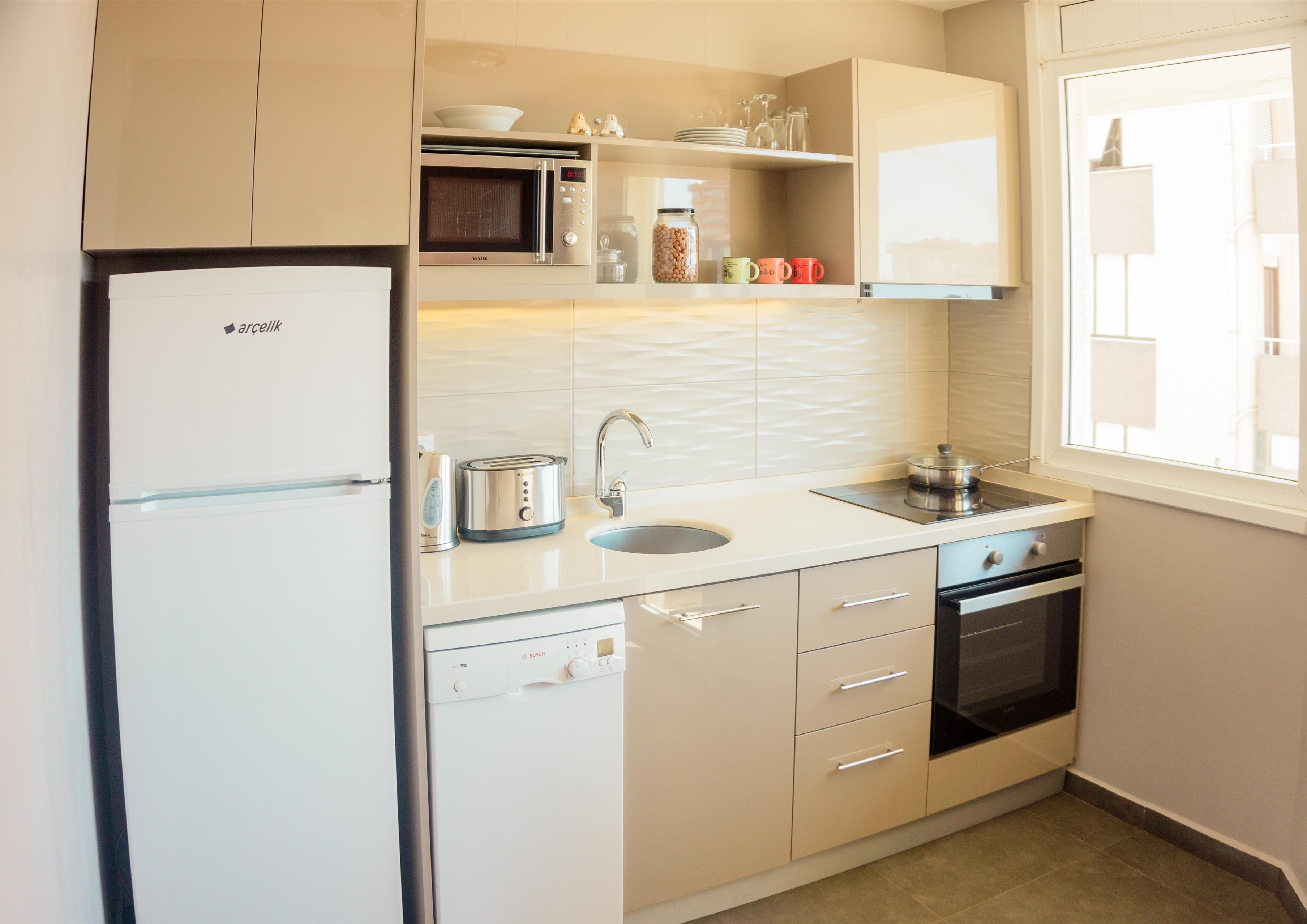 Una cocina moderna con lavavajillas Bosch, microondas, pileta y estufa.