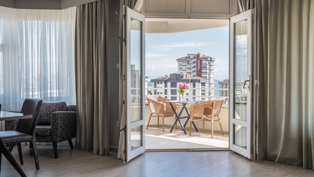 A modern hotel room with a balcony, a dining area, and a view of the cityscape. - The Marmara Suadiye Residence (Istanbul)