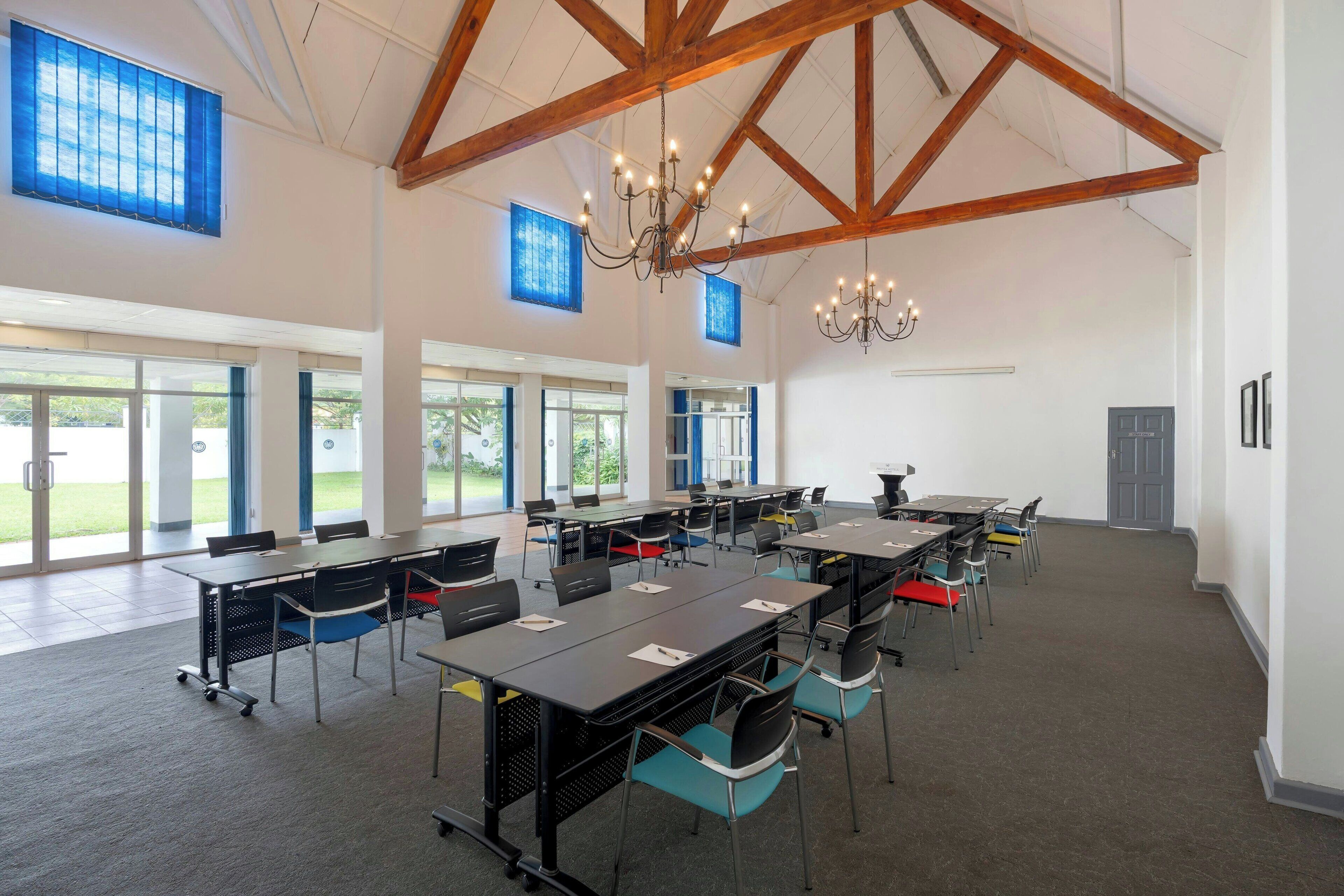 Una amplia sala de conferencias con techos altos, ventanas grandes y un candelabro.