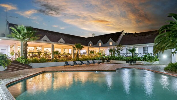 A pool area with lounge chairs and a building with a sloped roof. - Protea Hotel by Marriott Chingola (Chingola)
