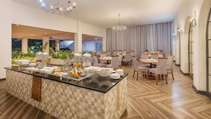 A spacious dining area with a buffet setup, featuring a central island with food and beverages, surrounded by dining tables and chairs. - Protea Hotel by Marriott Chingola (Chingola)