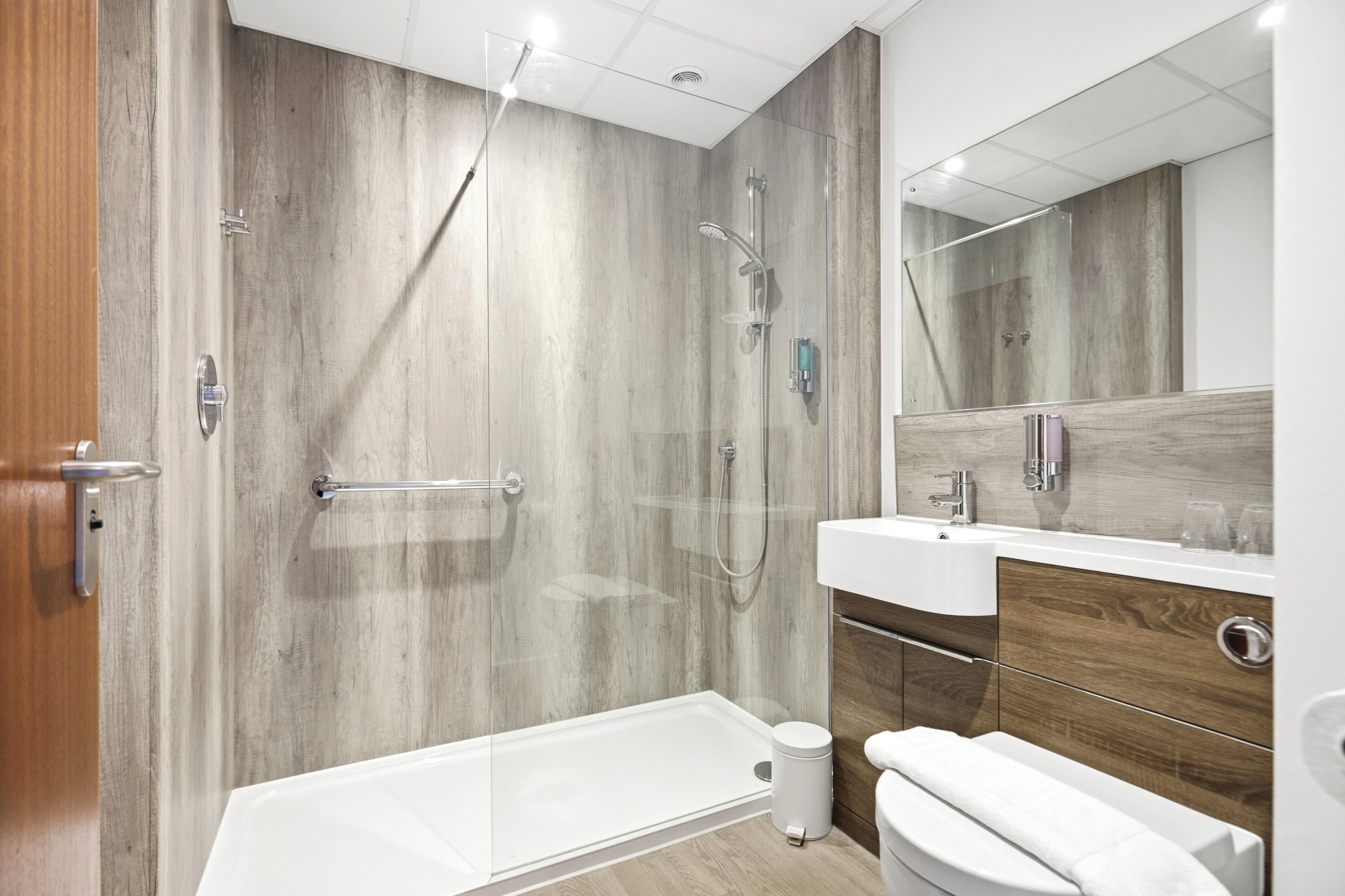 A modern bathroom with a walk-in shower, a bathtub, a toilet, and a vanity with a mirror.