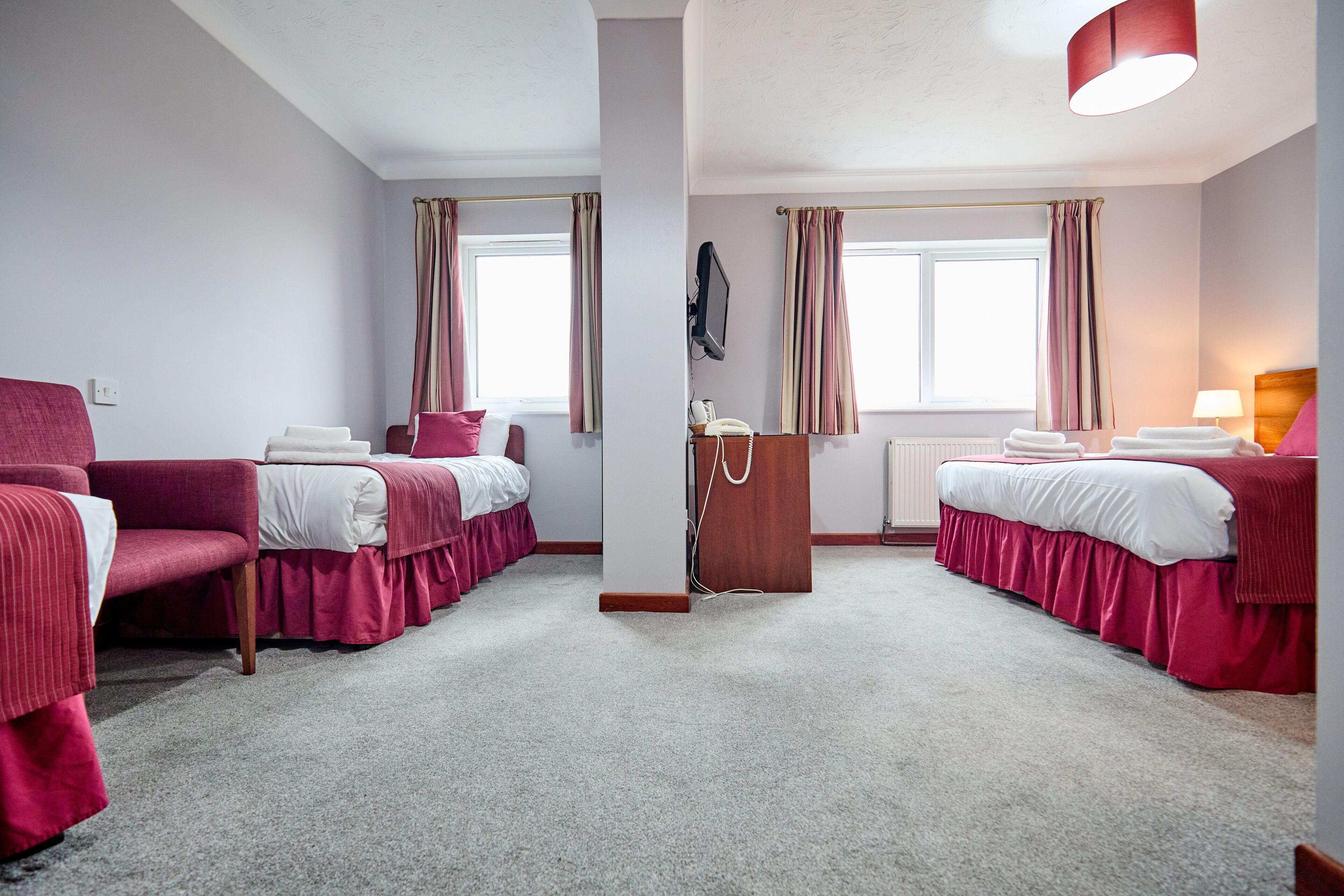 A hotel room with two beds, a desk, a chair, and a television.