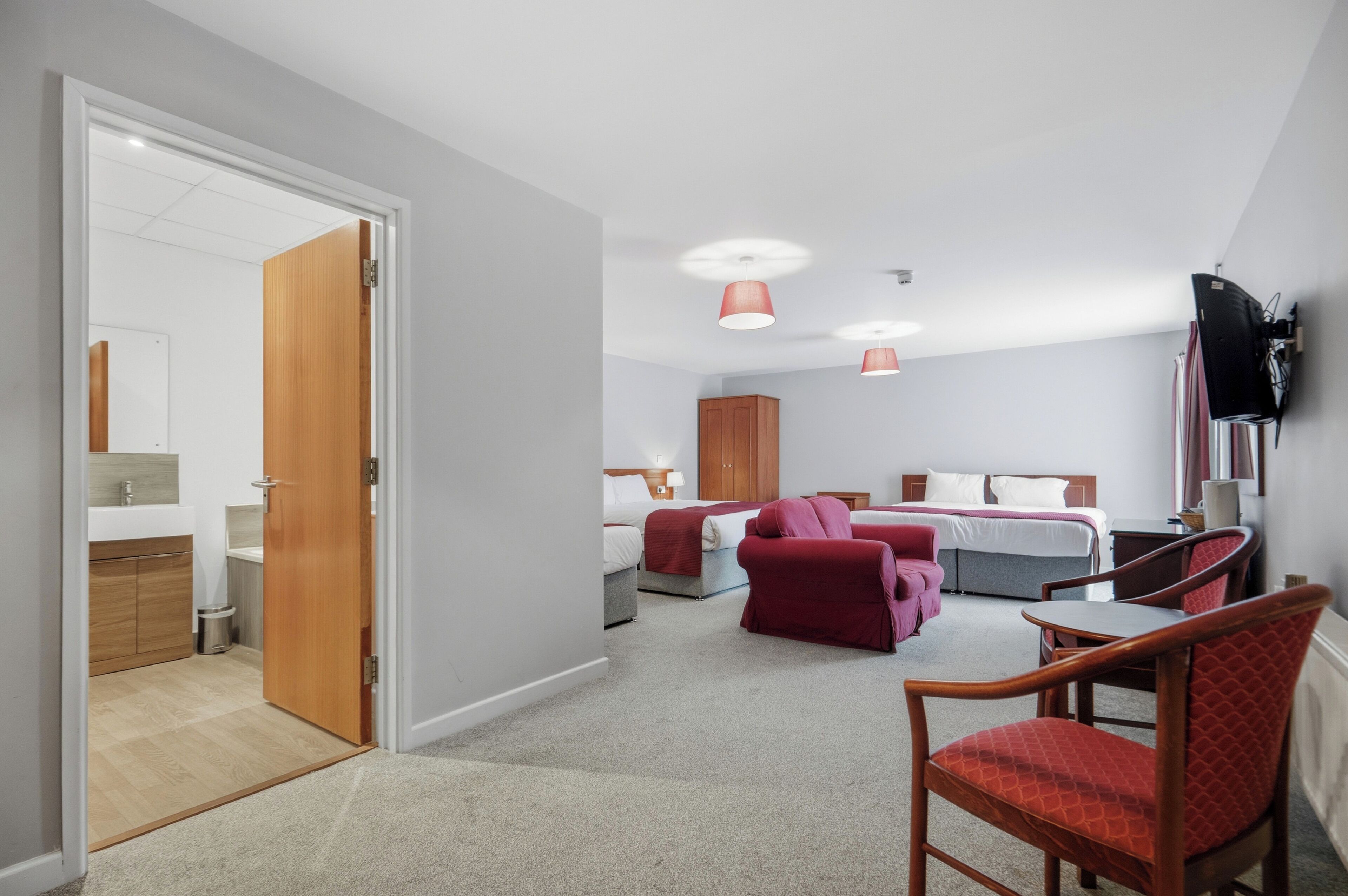 Una habitación de hotel con cama, escritorio, silla y televisión.