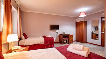 A hotel room with two beds, a desk, a TV, and a wardrobe.