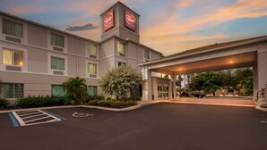 Un hôtel doté d’une tour centrale sur laquelle est affiché le nom de l’établissement, d’une entrée couverte et d’un parking aménagé pour les personnes handicapées.