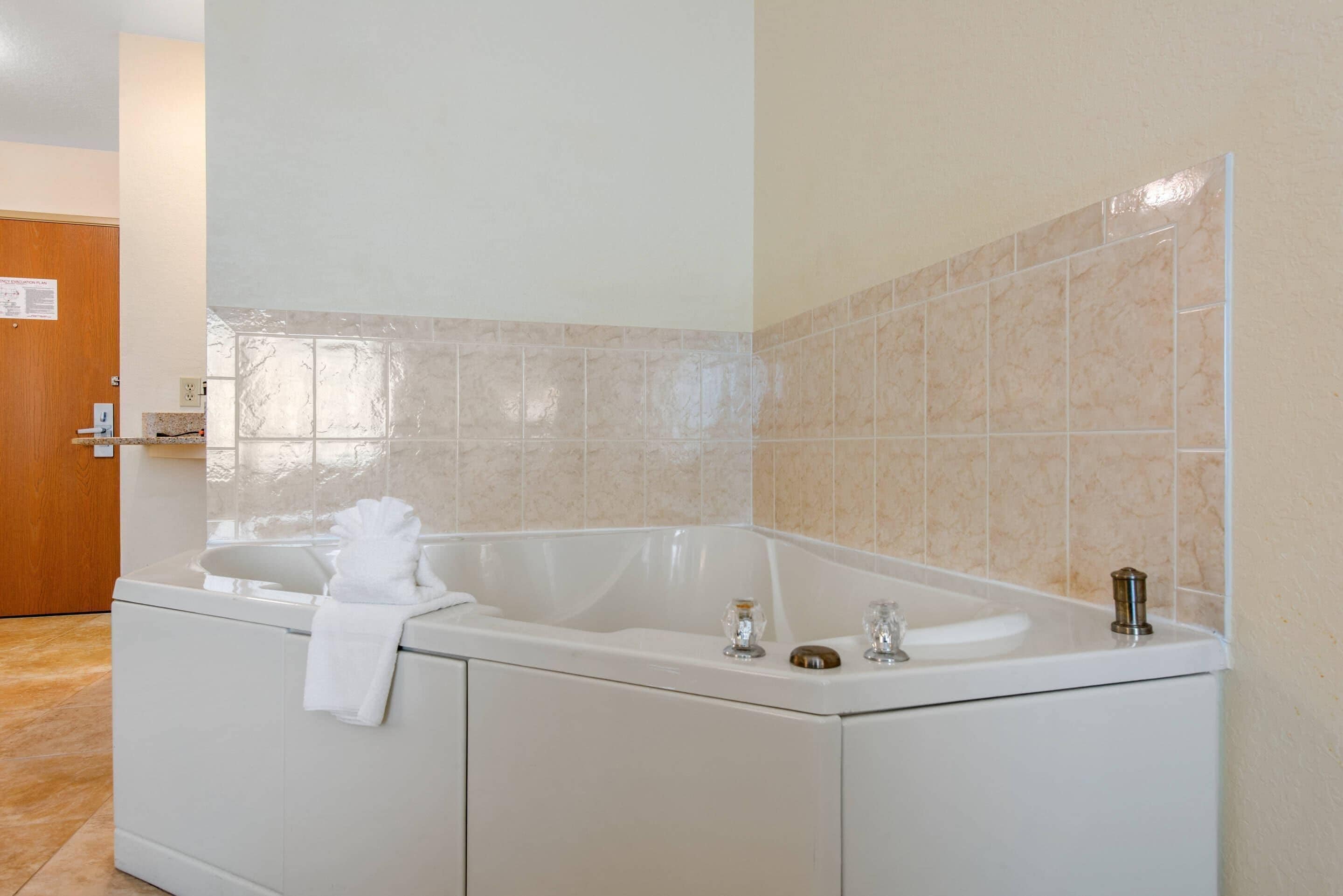 Un baño moderno con una bañera independiente, una toalla colgada en el lateral y un lavamanos pequeño.