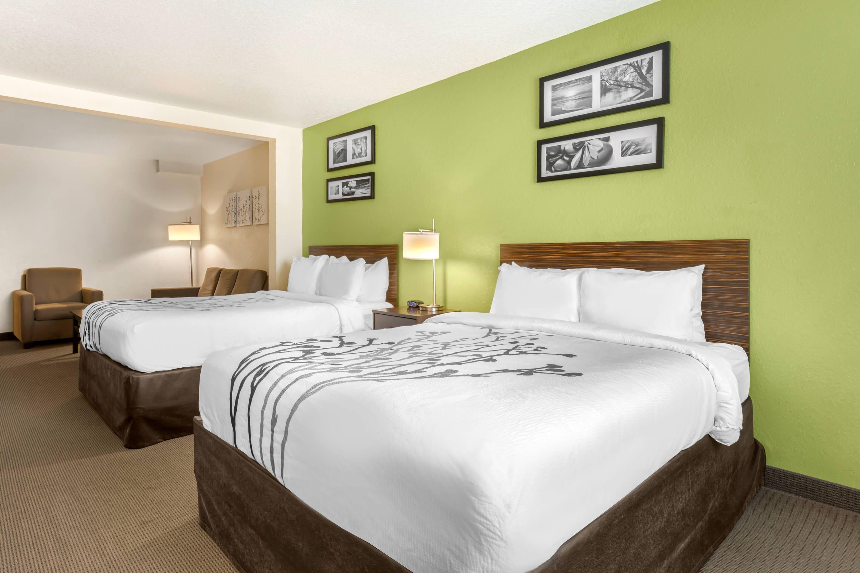 Une chambre d’hôtel avec deux lits, une chaise, une lampe et des tableaux encadrés au mur.