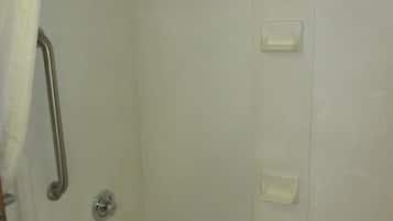 A bathroom with a bathtub, a shower, and a handrail.