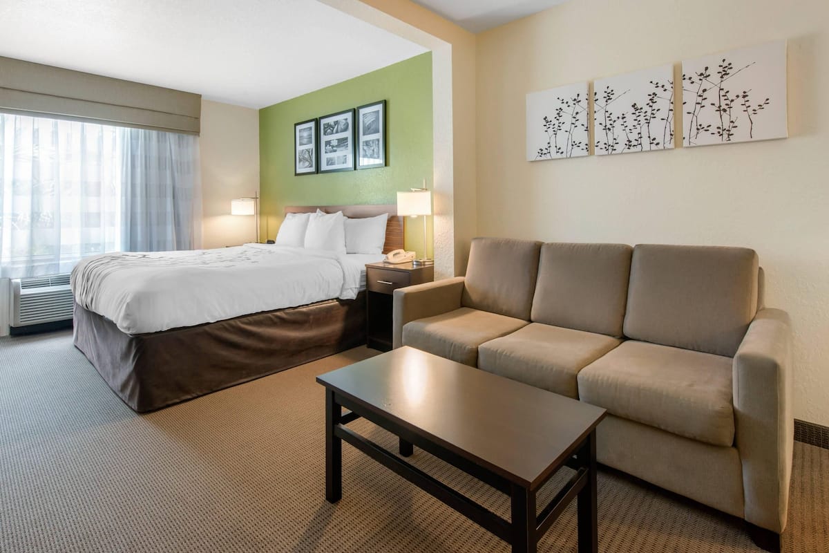 Ein Hotelzimmer mit Bett, einer Couch, einem Couchtisch und Wandbildern.