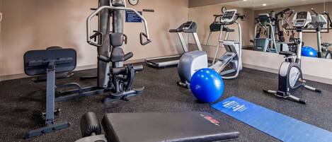 A gym with various exercise equipment including a treadmill, elliptical, and weight machines.