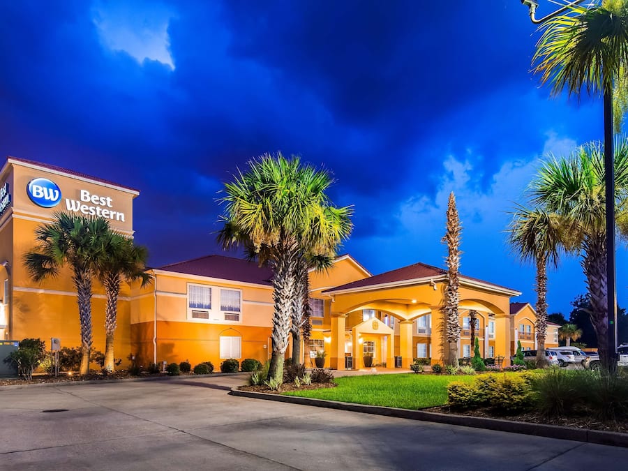 A Best Western hotel with a well-lit entrance, palm trees, and a clear sky.