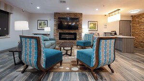 A modern living room with a stone fireplace, a flat-screen TV, and a bar area. - Best Western Lafayette Inn (Lafayette)