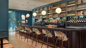 A bar area with a checkered floor, wooden bar counter, and multiple shelves of bottles. - The Gateway Hotel (Dundalk)