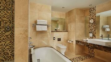 A modern bathroom with a bathtub, toilet, and shower area.
