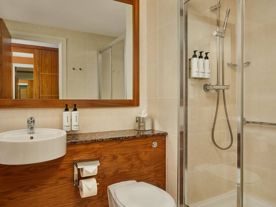 A bathroom with a wooden vanity, a sink, a toilet, and a glass-enclosed shower area.