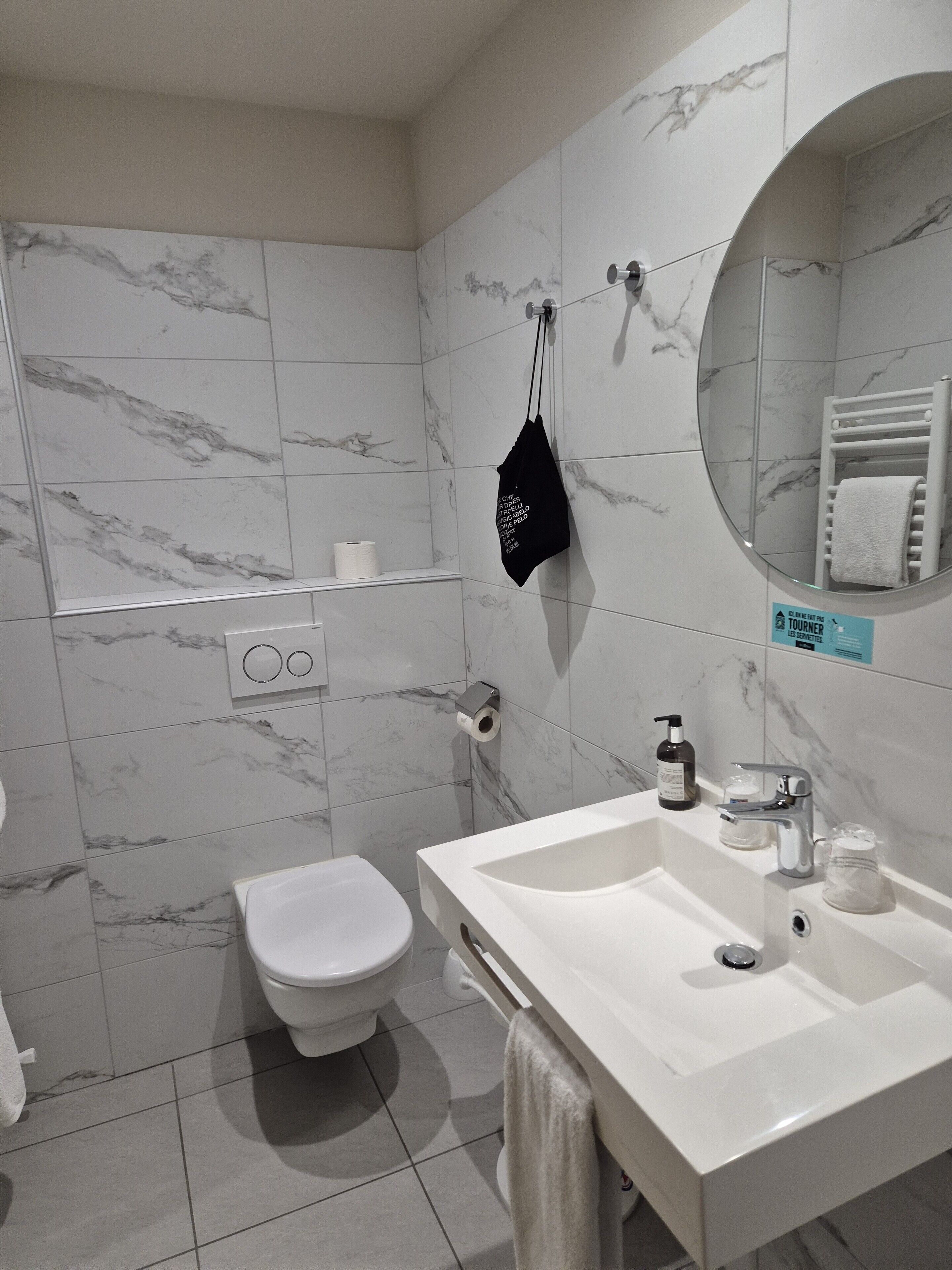 Uma casa de banho moderna com sanita, lavatório e espelho.