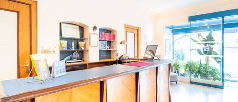 A reception desk with a wooden finish, a reception area with a counter, a phone, and a framed certificate on the wall.