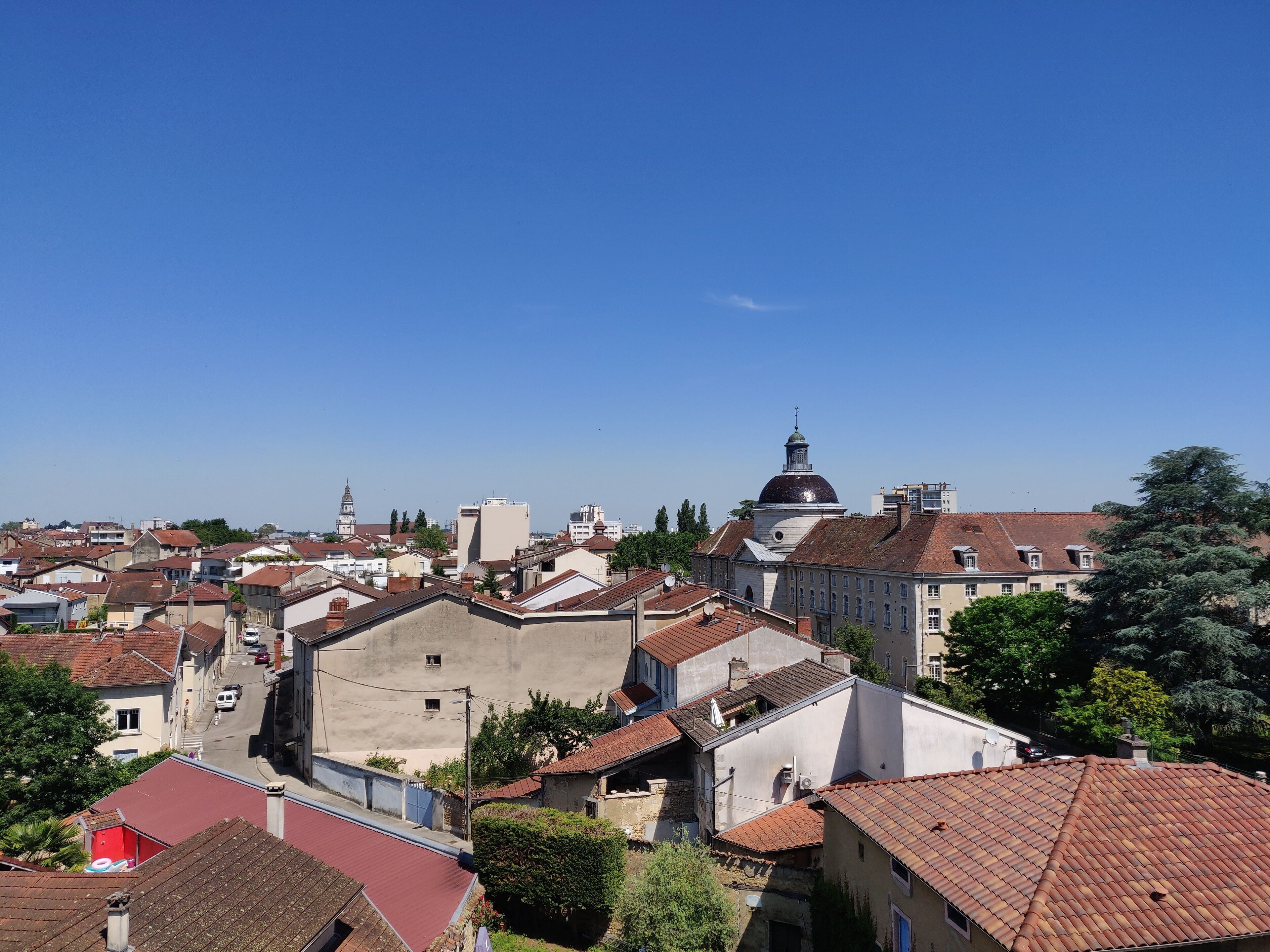 A cityscape with a prominent church with a dome and a bell tower, surrounded by residential buildings with red-tiled roofs.