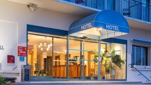A hotel entrance with a blue awning, glass doors, and a reception desk visible inside. - Cit'Hotel Logis de Brou (Bourg-en-Bresse)
