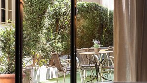 A room with a view of an outdoor patio area featuring wicker furniture and potted plants.